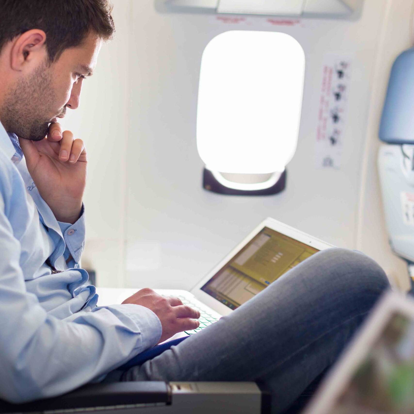 Businessman working with laptop on airplane.