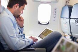 Businessman working with laptop on airplane.