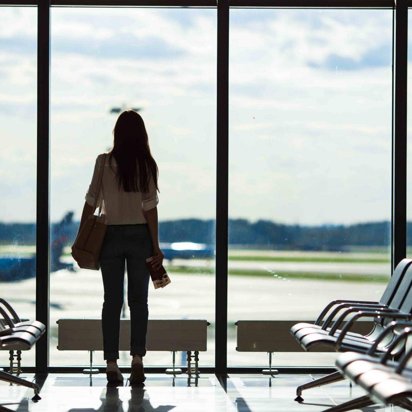 Silhouette of woman in an airport lounge waiting for flight aircraft