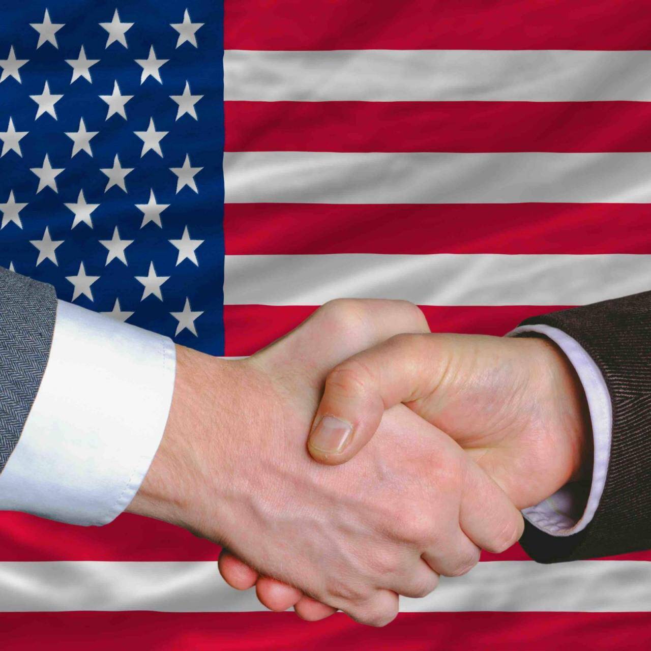 businessmen handshake after good deal in front of america flag