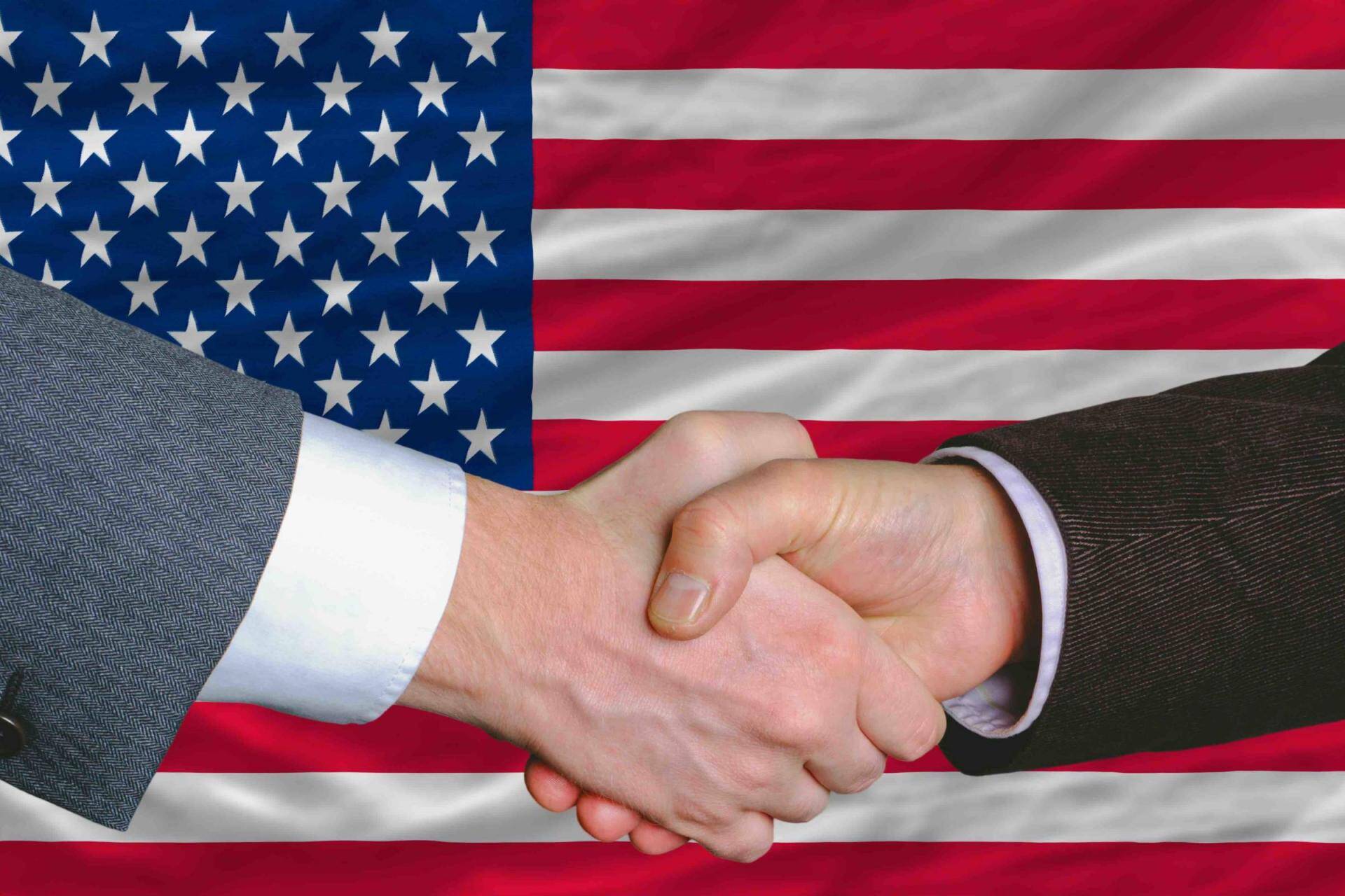 businessmen handshake after good deal in front of america flag