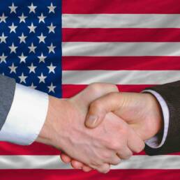 businessmen handshake after good deal in front of america flag