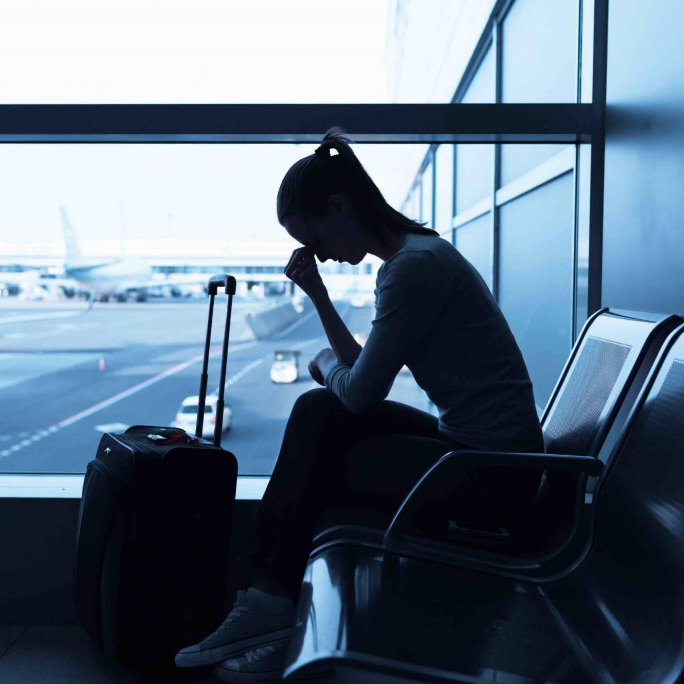 Sad/stressed/sick woman at airport holding a smartphone.