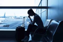 Sad/stressed/sick woman at airport holding a smartphone.