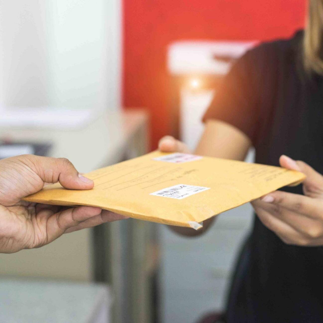 male hand send mail envelope to the female of post office before sending