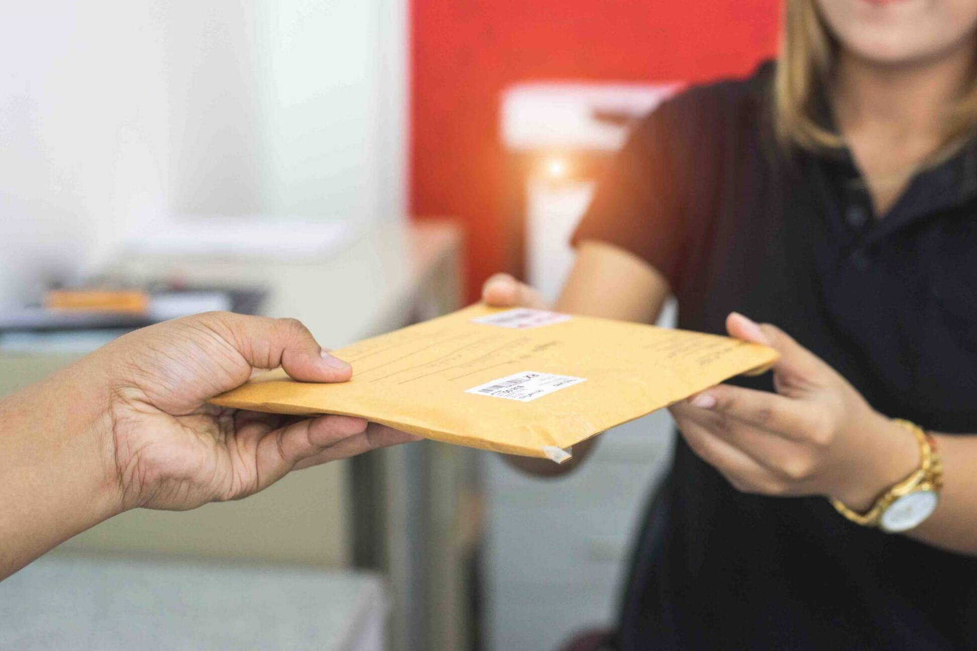 male hand send mail envelope to the female of post office before sending