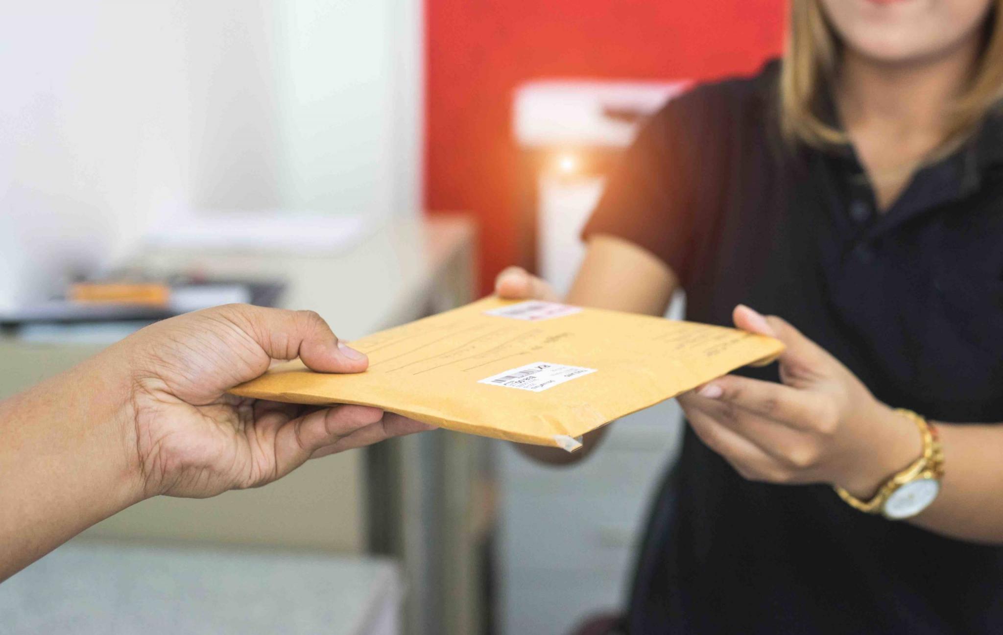 male hand send mail envelope to the female of post office before sending