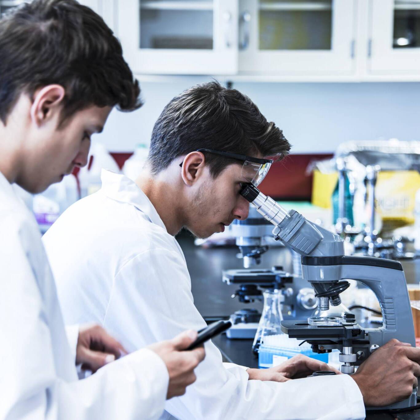 Science research project conducting with two young male scientific researchers in laboratory