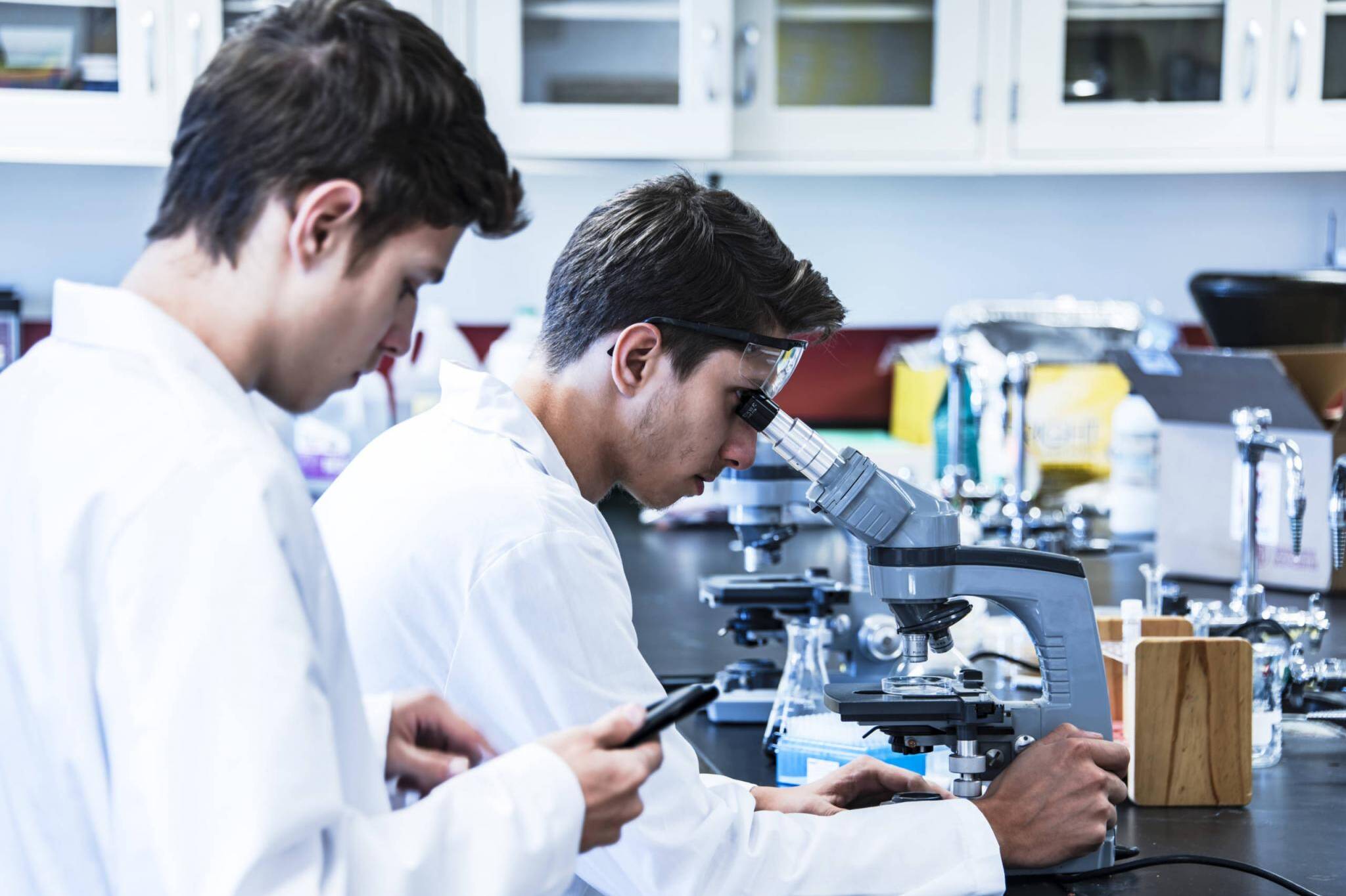 Science research project conducting with two young male scientific researchers in laboratory