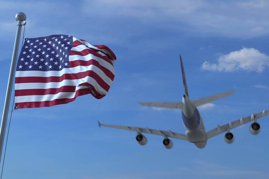 Commercial airplane landing behind waving American flag. Travel to the United States conceptual 3D rendering