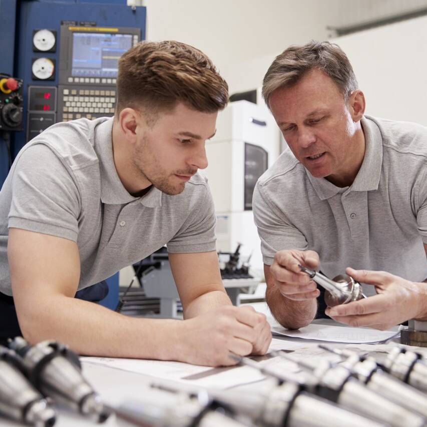 Engineer Showing Apprentice How To Measure CAD Drawings