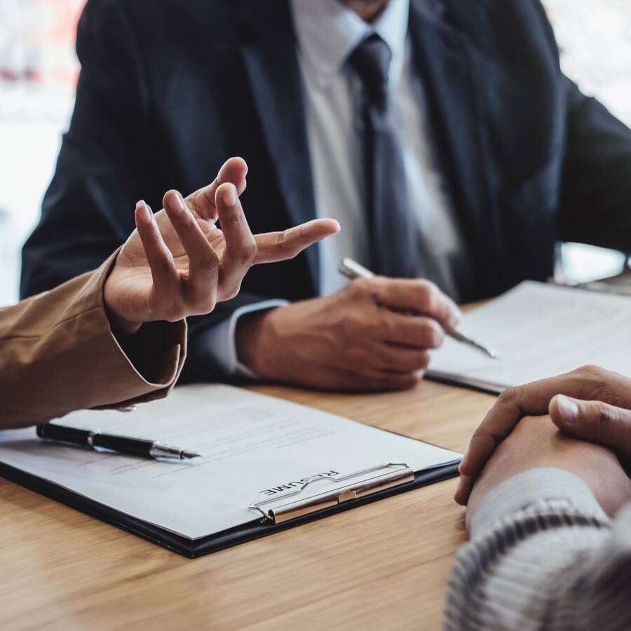 Two senior manager reading a resume during a job interview, Employer interviewing to ask young male job seeker for recruitment talking in office