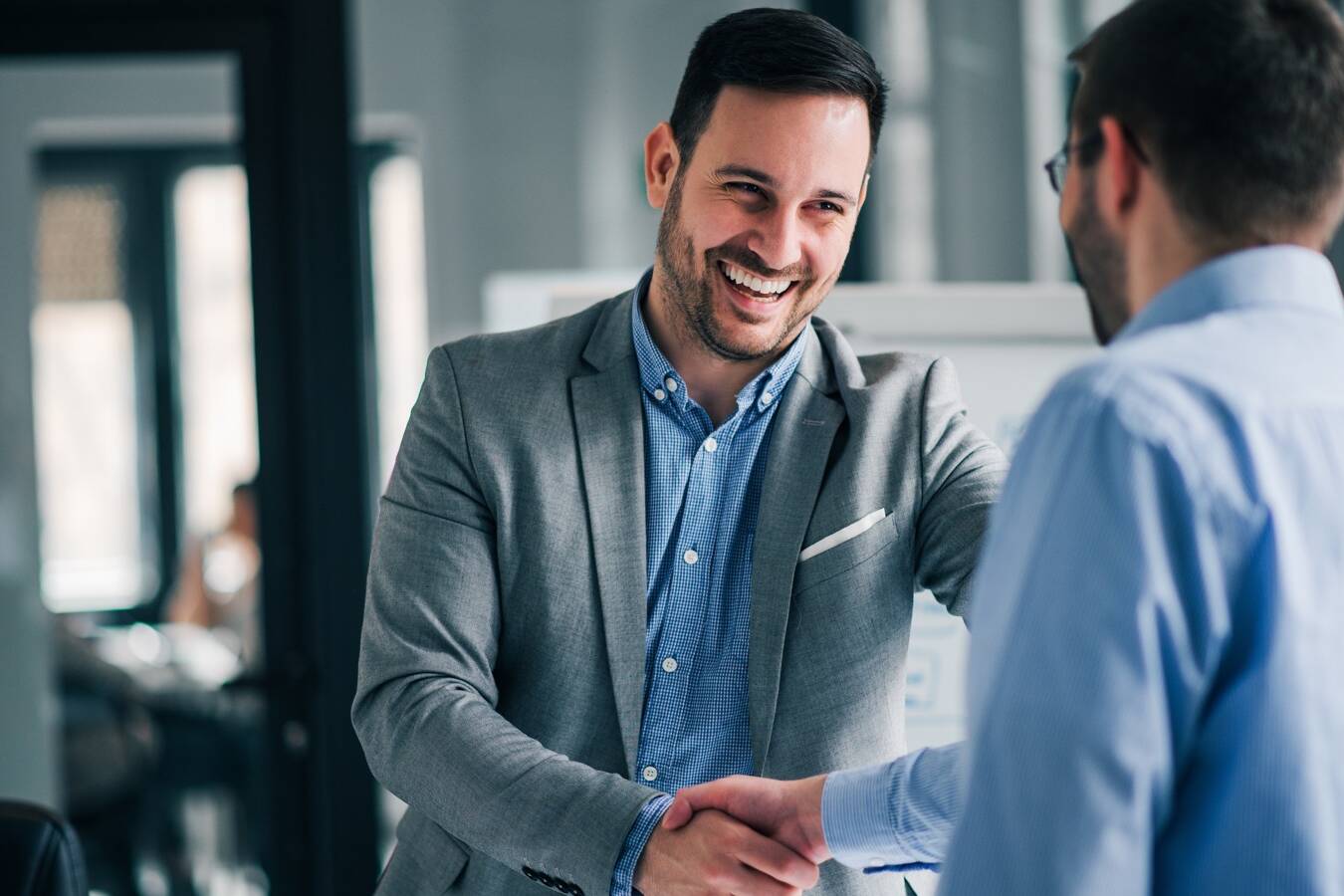 Portrait of cheerful young manager handshake with new employee.