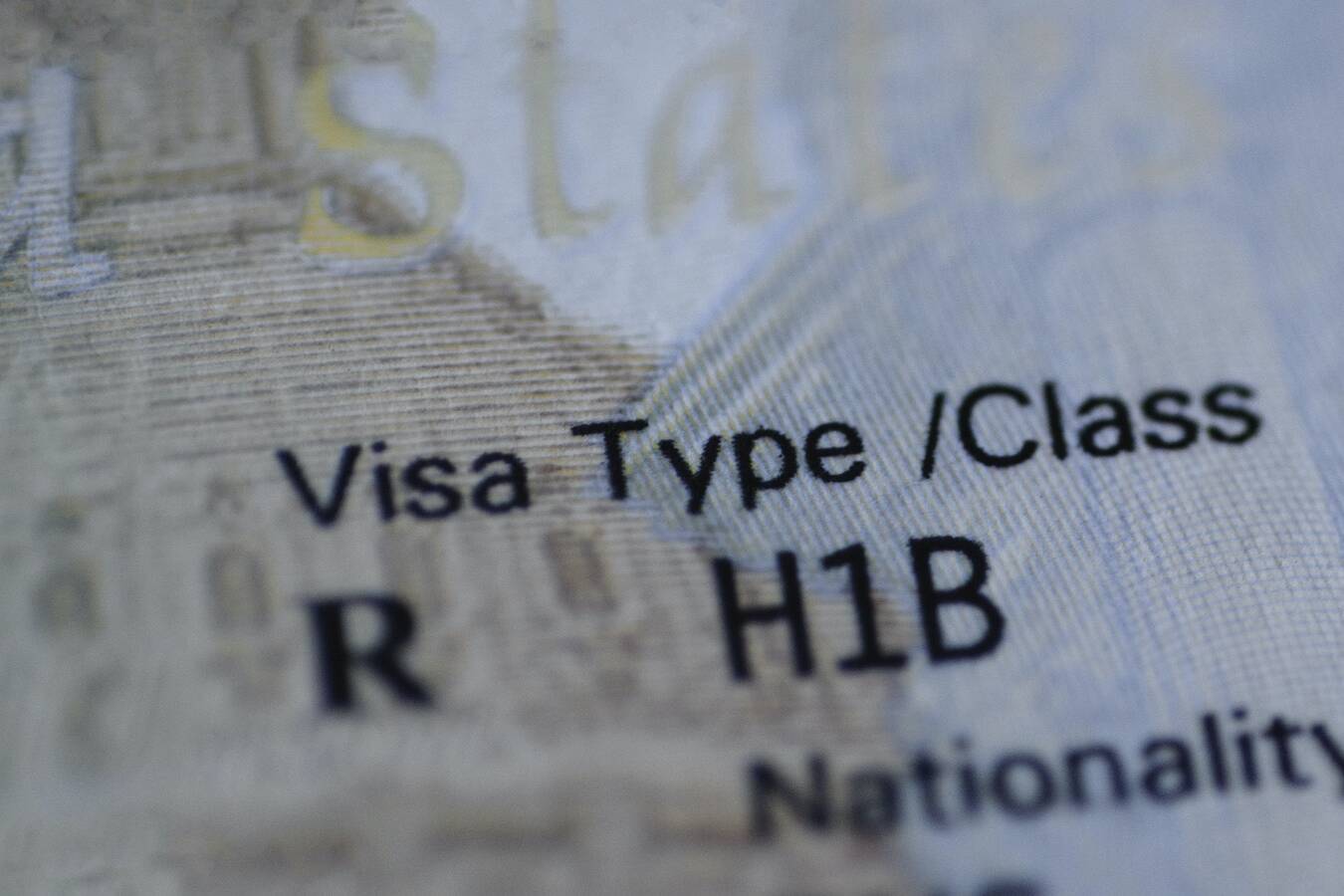 Fragment of H1B visa (for specialty workers) stamp in passport, blurred april calendar on background. H1B visa program deadline concept. Close up view.