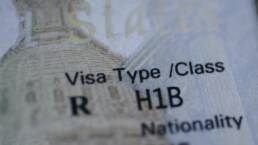 Fragment of H1B visa (for specialty workers) stamp in passport, blurred april calendar on background. H1B visa program deadline concept. Close up view.