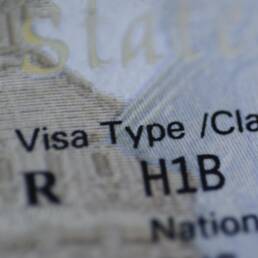 Fragment of H1B visa (for specialty workers) stamp in passport, blurred april calendar on background. H1B visa program deadline concept. Close up view.