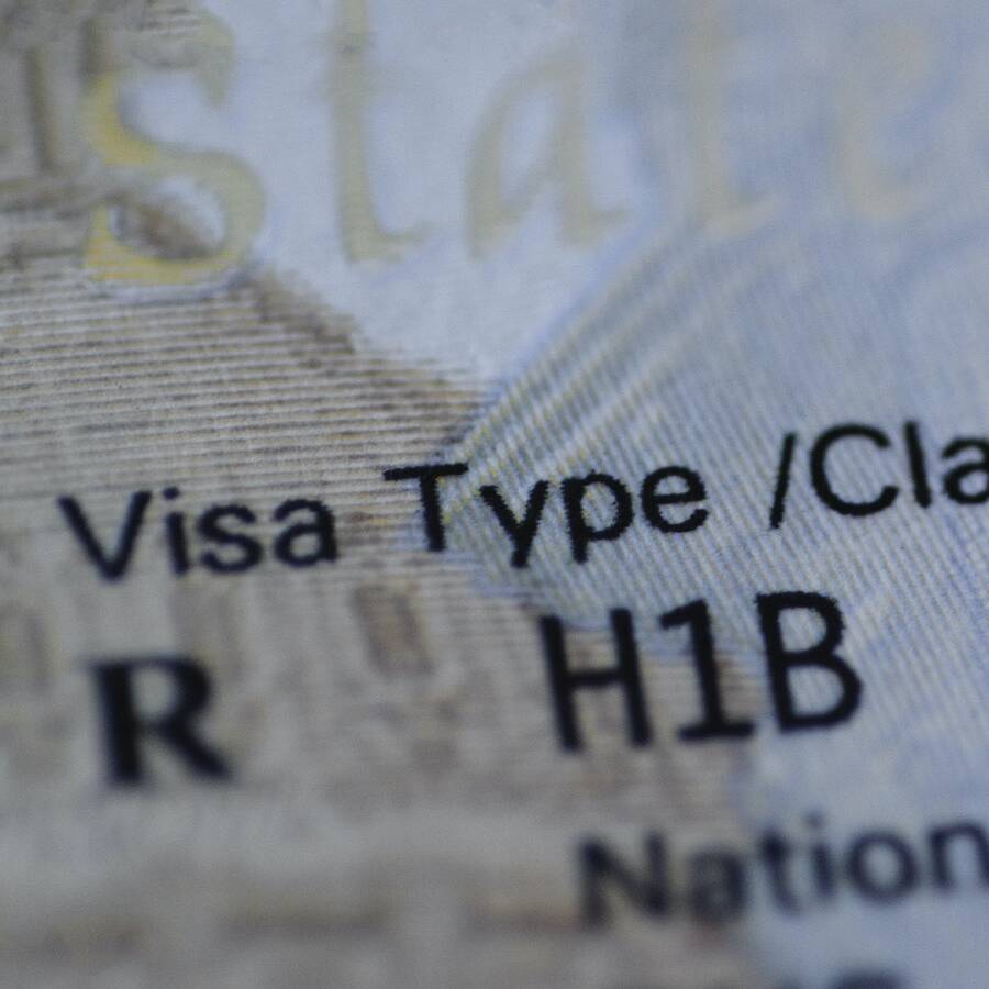 Fragment of H1B visa (for specialty workers) stamp in passport, blurred april calendar on background. H1B visa program deadline concept. Close up view.