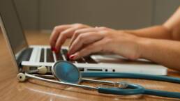 hands on keyboard with stethoscope nearby