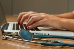 hands on keyboard with stethoscope nearby