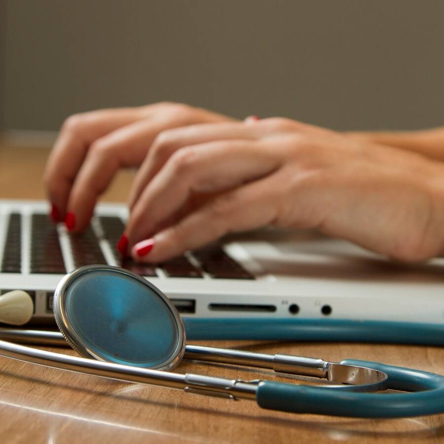 hands on keyboard with stethoscope nearby