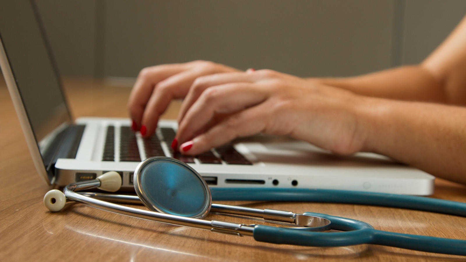 hands on keyboard with stethoscope nearby